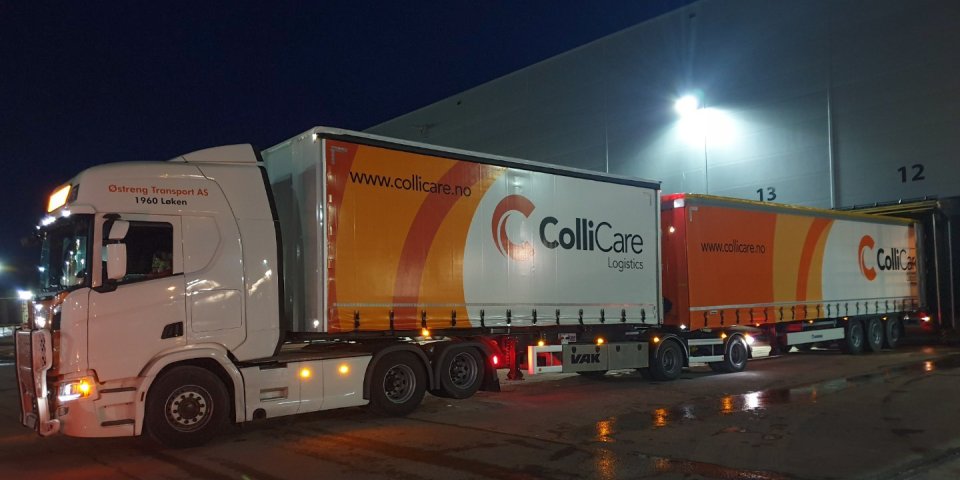 A branded ColliCare-trailer at night, parked at the terminal to unload goods.