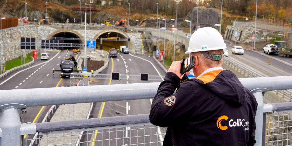 Employee in branded clothes talking on the phone and looking down on the freeway in Norway from a bridge