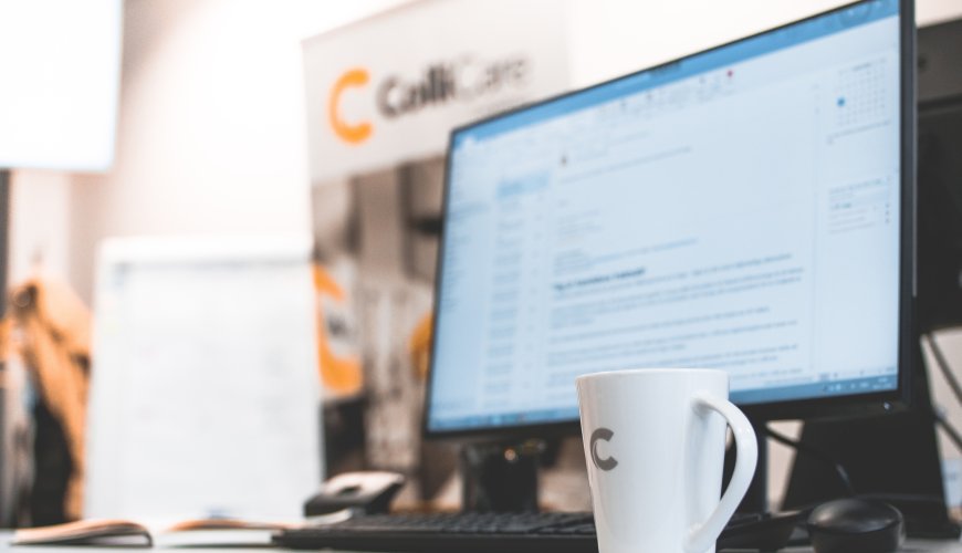 A computer at a desk surrounded by branded ColliCare mug and banner