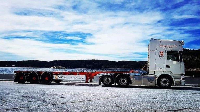 A branded ColliCare truck on the road by the ocean in Norway, ready to transport goods and cargo