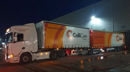 A branded ColliCare-trailer at night, parked at the terminal to unload goods.