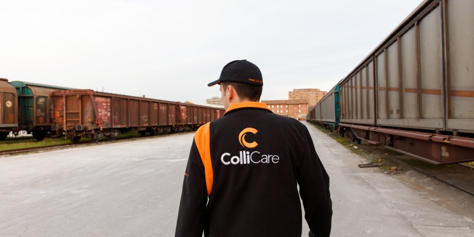 En ansatt i merkede ColliCare klær som går mot et parkert tog på togstasjonen 